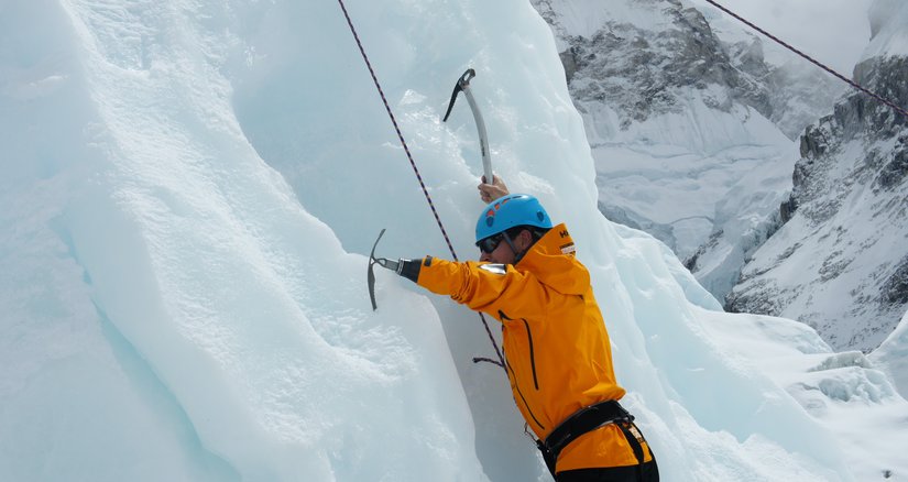 A person climbing a mountain with an ice pick